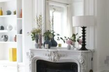 a French fireplace with a gorgeous mantel, a built-in mirror with frame as part of molding, a black screen a a built-in bookcase next to it