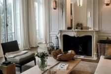 a French style living room done in neutrals, stylish seating furniture, a low coffee table, a French fireplace and an oversized mirror