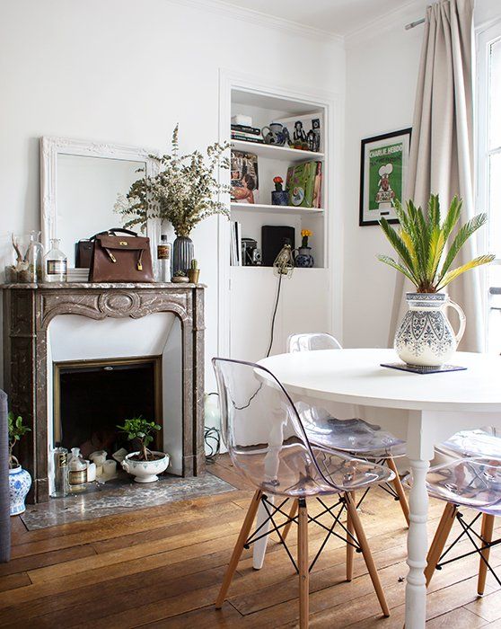 a Scandi dining room with a built-in storage unit, a French fireplace clad with marble, a white table and acrylic chairs