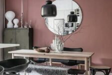 a Scandinavian dining room with mauve walls, chic furniture, an olive green buffet, black touches and a round mirror