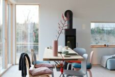a Scandinavian dining space with a pallet dining table, matching pastel chairs and cushions and a pink vase is airy and cool