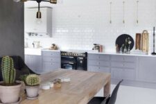 a Scandinavian kitchen with grey and white cabinets, white subway tiles, a wooden table and black chairs is very fresh