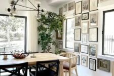 a beautiful dining room with a light-stained table and mismatching chairs, a chic chandlier and a monochromatic gallery wall