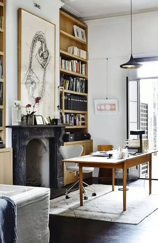 a beautiful modern Victorian home office with built-in bookcases, a non-working French fireplace, a simple and a neutral chair, a black pendant lamp