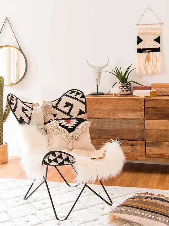 a bold boho space with a dresser with mismatching drawers, a bright boho print butterfly chair, a rug and pillows and a macrame hanging