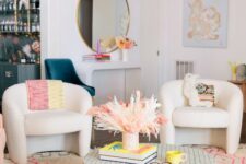 a bright and whimsy living room with a curved console and a round mirror, curved chairs, a round coffee table and pink touches