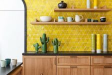 a bright mid-century modern kitchen with a bold yellow tile wall, wooden furniture, black countertops, wicker chairs and funny tableware