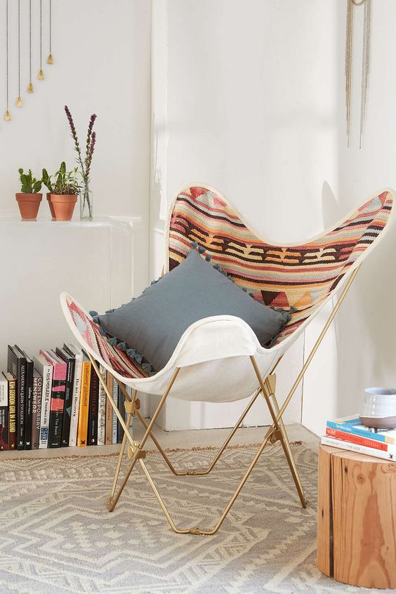 a butterfly chair with a bright printed boho cover and a grey pillow is a cool idea for a boho space