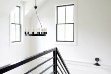 a catchy black and white farmhouse space with paneling and black touches – double-hung windows, railing and a chandelier