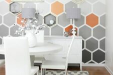a catchy dining space with a hexagon accent wall, white furniture, a printed rug, coral and gold touches