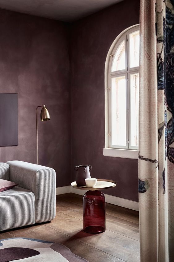 a catchy mauve living room with a low neutral sofa, a side table, a brass floor lamp is a very elegant and chic space