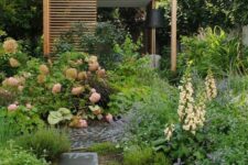 a catchy modern garden with lush and textural greenery and blooms, a tile path, a terrace done with wood