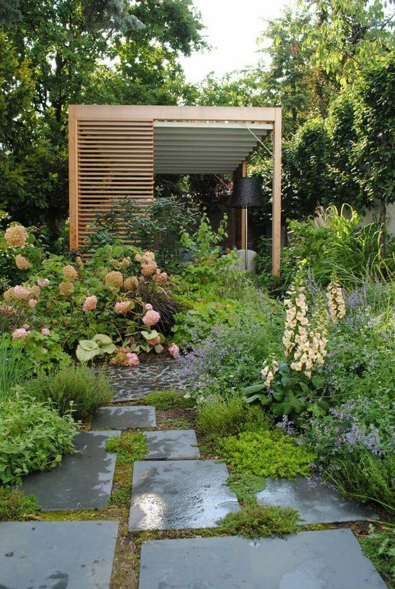 a catchy modern garden with lush and textural greenery and blooms, a tile path, a terrace done with wood