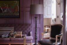 a chic and refined living room with a purple accent wall, a purple sofa and a black leather chair, a coffee table and a floor lamp