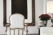 a chic neutral living room with a statement artwork, a creamy sofa, a creamy antique chaira woven bench and a neutral rug