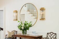 a cihc entryway with a vintage stained table, antique chairs, a round mirror in a gold frame and vintage sconces