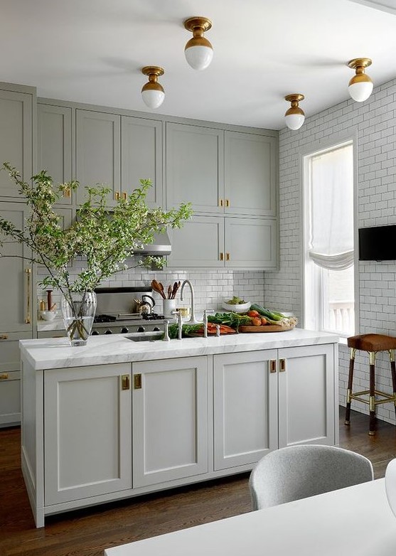 a classic grey kitchen with beautiful brass accents and flush mount lighting and white subway tiles on two walls