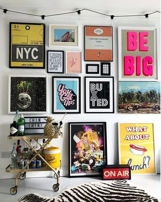 a colorful pop art gallery wall in various colors - posters for fun and with black and white frames is a bold idea