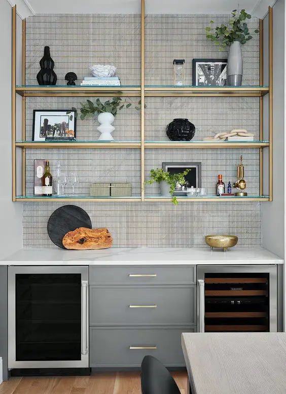 a contemporary kitchen with grey cabinets, a glass shelving unit with gold touches is a chic and cool idea