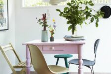 a cool dining space with a pink vintage table, mismatching pastel chairs, a pendant lamp and greenery is all cool