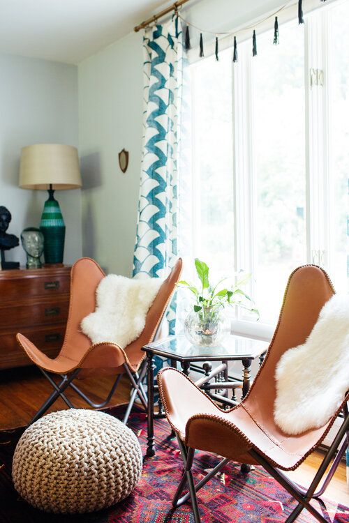a cool mid-century meets boho nook with a geometric coffee table, amber leather butterfly chairs and white faux fur