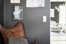 a cozy nook with a brown leather butterfly chair, a matching striped pouf, a gallery wall and a grey pillow