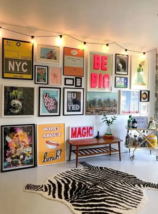 a creative gallery wall with bold and unusual artworks and posters in mismatching frames is a very bold idea