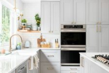 a dove grey kitchen with shaker cabinets with white countertops, a white tile backsplash, brass handles