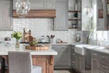 a farmhouse slate grey kitchen with shaker style cabinets, a stained kitchen island and a hood, white stone countertops and pendant lamps