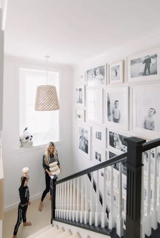 a free form staircase gallery wall with black and white family pics and white frames is a very chic and stylish idea for any space