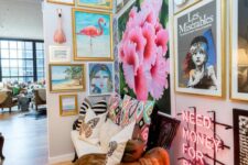 a fun and bright floor to ceiling gallery wall that takes two walls, a loveseat with colorful pillows and a neon sign