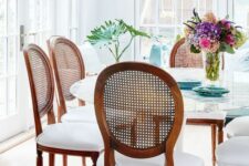 a large round table and dark-stained antique ones in a light-filled sunroom thta is a dining space