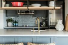 a light grey and graphite grey kitchen with a grey tile backsplash, suspended shelves, woven stools and brass and gold fixtures