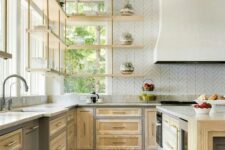 a light-stained farmhouse kitchen with shaker cabinets, a large hood, suspended shelves and a kitchen island