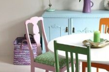 a lovely bright and pastel dining nook with a blue credenza, a round table, mismatching pastel chairs and a purple rug