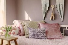 a mauve bedroom with a single bed, a stool and pink bedding plus creative art on the wall