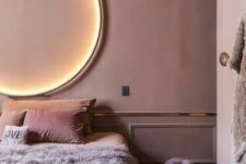 a mauve bedroom with gold edge, a lit up circle lamp and pink and lavender bedding is very refined
