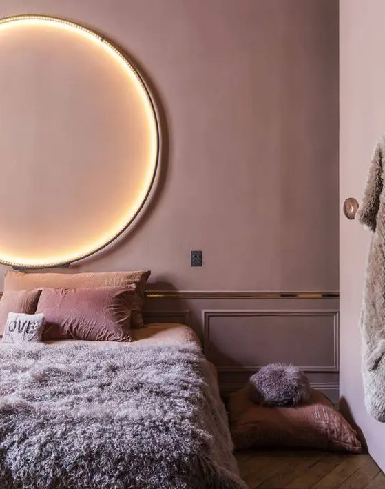 a mauve bedroom with gold edge, a lit up circle lamp and pink and lavender bedding is very refined