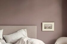a mauve bedroom with neutral furniture, a pink blanket and neutral bedding and bold artworks