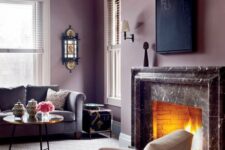 a mauve living room with a marble clad fireplace, a grey sofa, a neutral chair, a coffee table and a black sconce