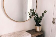 a minimal boho entryway with a wooden bench, a printed rug, a faux fur cover and a potted plant plus a round mirror
