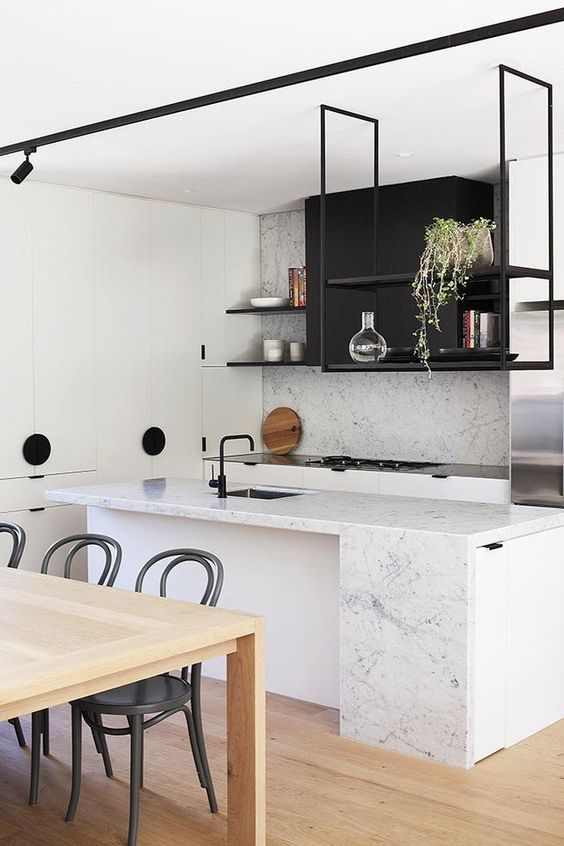 a modern black and white kitchen with white stone countertops and a backsplash, a black suspended shelf and potted greenery