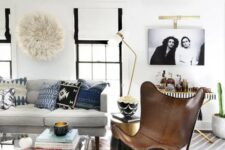 a modern boho living room with a grey sofa, a brown butterfly chair, an acrylic coffee table, a printed rug and pillows
