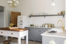 a modern country style kitchen with grey cabinets and a white kitchen island, pendant lamps and touches of gold