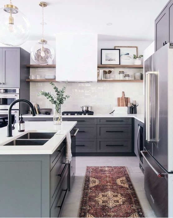 a modern farmhouse kitchen with grey cabinets, a white hood and tile backsplash and white countertops plus a boho rug