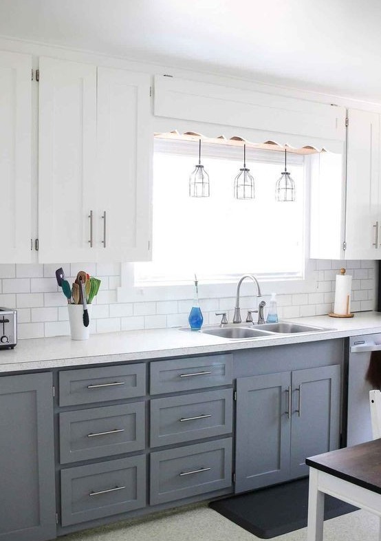 a modern farmhouse kitchen with upper white cabinets, lower grey ones, pendant lamps and metallic touches here and there