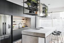 a modern industrial kitchen in black, with built-in shelves, a concrete kitchen island, suspended shelves over it and black stools