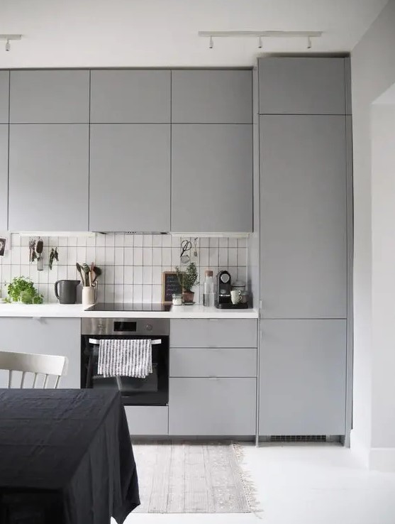 a modern light grey kitchen with a white tile backsplash made stand out with black grout