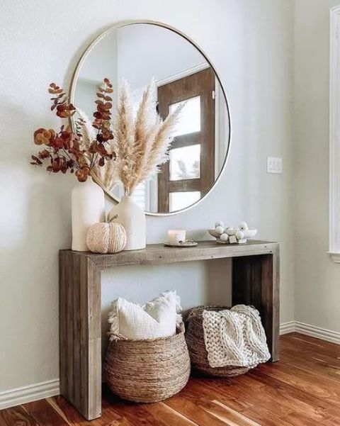 a modern rustic entryway with a stained console, baskets for storage and some lovely fall decor plus a round mirror