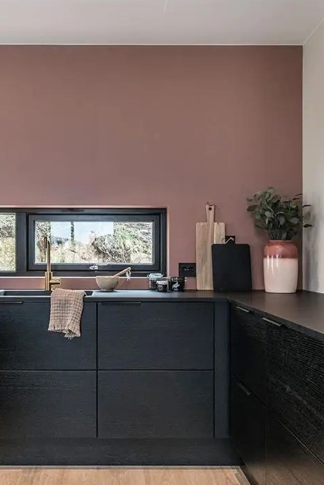 a moody mauve kitchen with lower black cabinets, a window backsplash and various neutral and black accessories